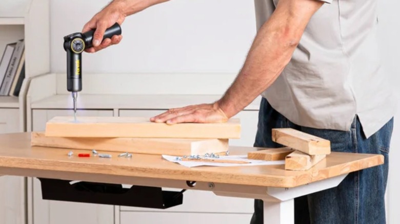 Person using a Fanttik S1 Apex Electric Screwdriver to screw into a wood plank