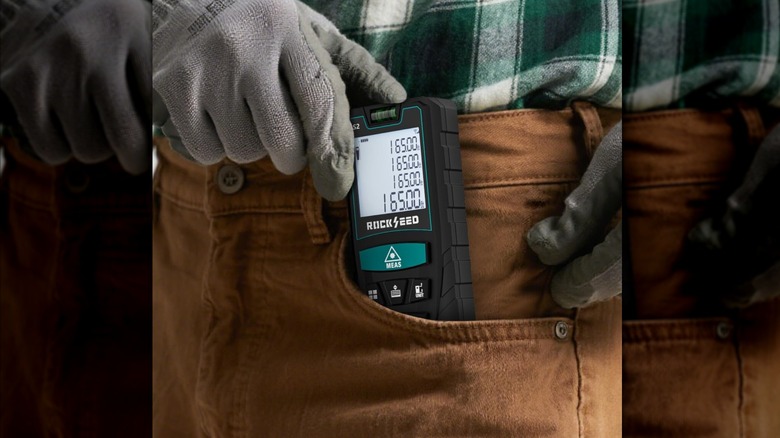Person inserting RockSeed laser measuring tool into trouser pocket
