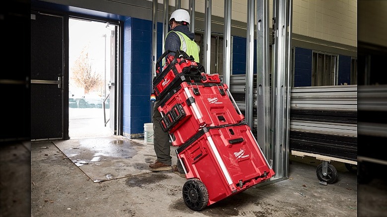 Worker transporting Packout toolboxes out of a facility.