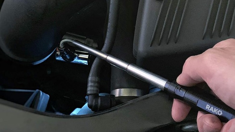 A person inspecting an engine with the Rak Magnetic Pickup Tool.