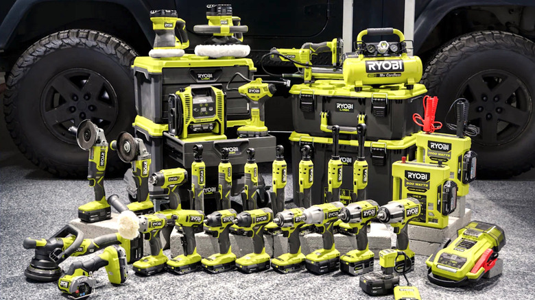 Multiple Ryobi automotive tools in front of vehicle