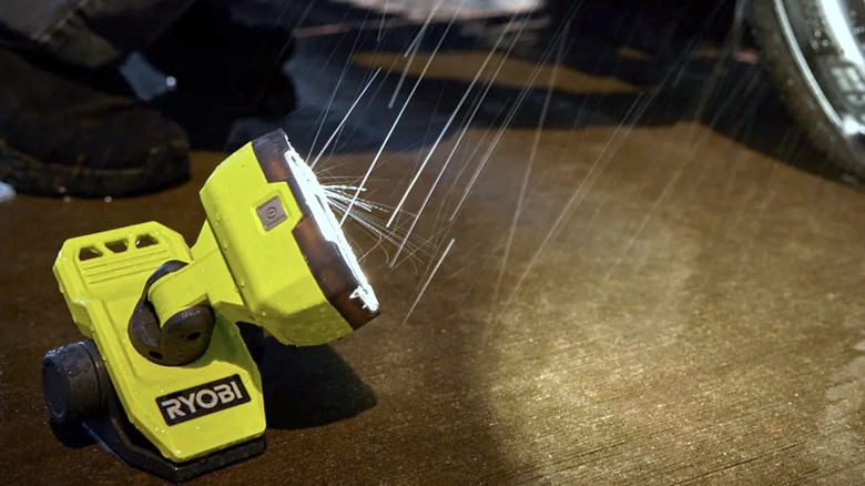 Person using Ryobi clamp light to illuminate tire