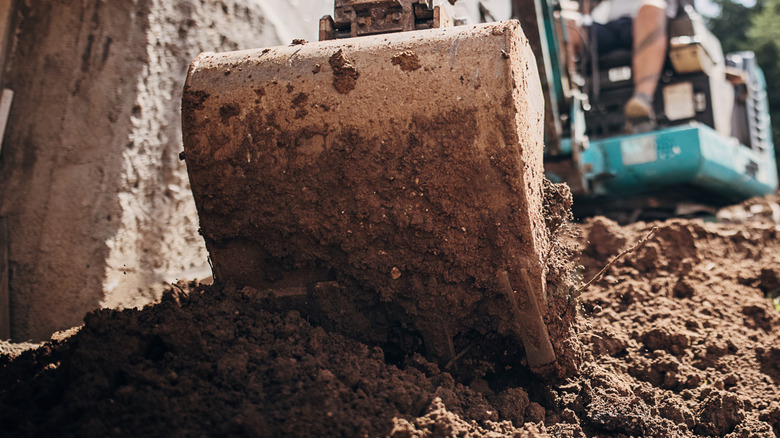 Person backfilling dirt with Harbor Freight backhoe