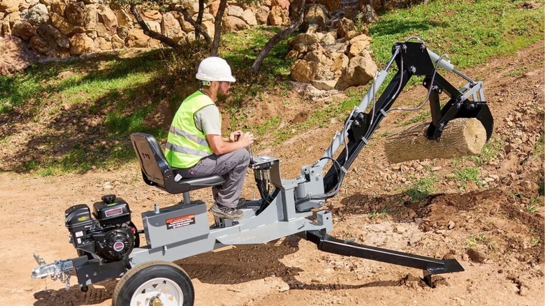 Person using Harbor Freight backhoe to move wood