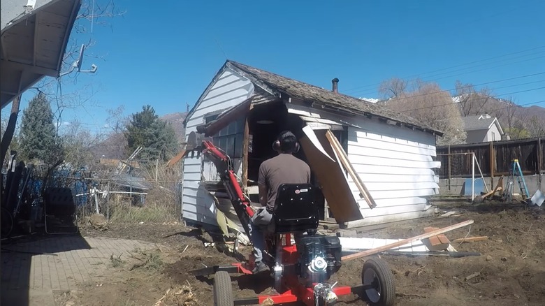 Person using Harbor Freight backhoe for demolition