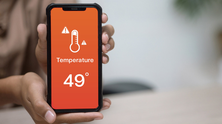 A phone showing a temperature alert for 49 degree Celsiuson on its screen
