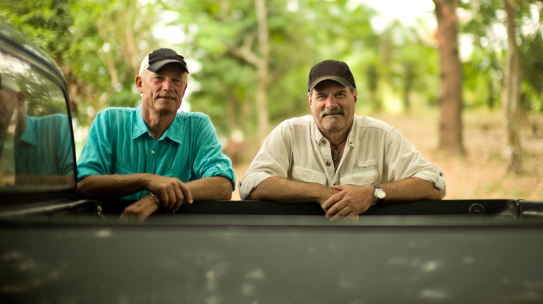 Two men leaning over truck bed