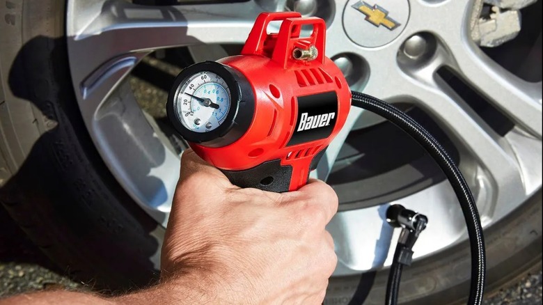 A person inflating a car tire with the Bauer cordless inflator from Harbor Freight.