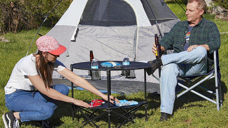 people camping outside with tent and table