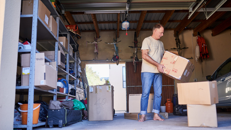A man organizing his garage space with metal shelves, wall mounts, and boxes