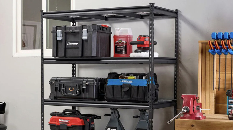 The five-tier steel shelf from U.S. General sold by Harbor Freight sitting against a gray wall with various boxes and tools on it