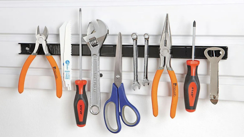 Harbor Freight's magnetic tool holder attached to a white wall and holding tools, scissors, and more