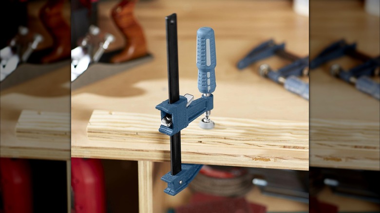 A Pittsburgh Quick Release Bar Clamp holding a piece of wood to a work table.