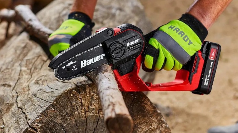 A person using a Bauer pruning saw on wood.