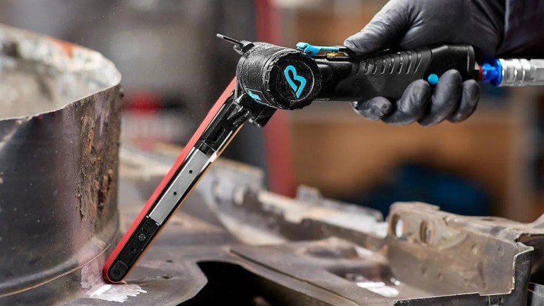 A person using a Baxter air sander on metal.
