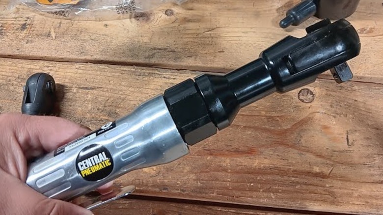 A person holding a Central Pneumatic air ratchet wrench.