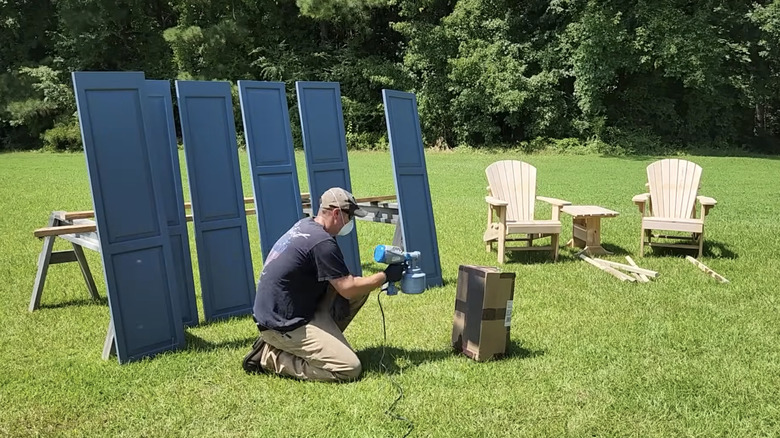 man using paint sprayer on box