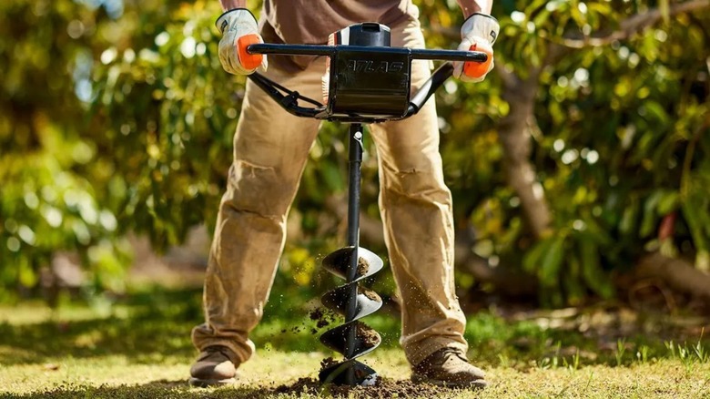 Man using Atlas Cordless Auger to drill hole