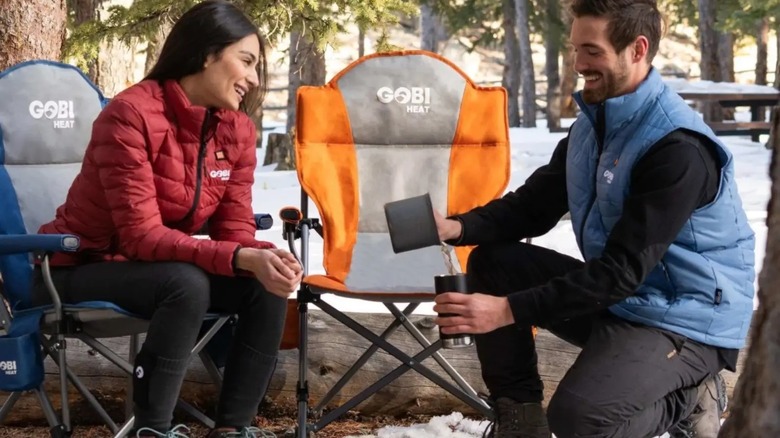 Two people outside with camping chairs