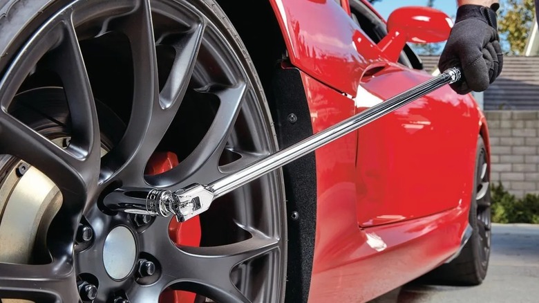 A mechanic loosening the lug nut on a car tire with an Icon breaker bar.