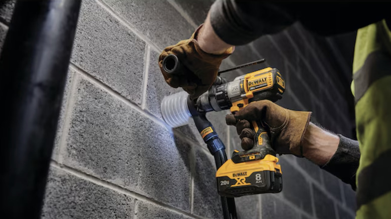 man using hammer drill on brick