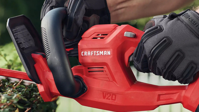 close-up of a person using Craftsman V20 20-inch Cordless Hedge Trimmer