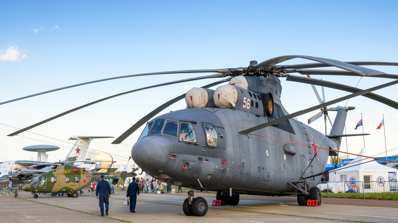 Mil Mi-26 Halo parked on stand with two personnel inspecting the vehicle, front-portside view