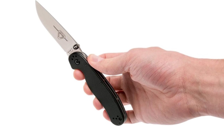 Person holding a folding knife on white background