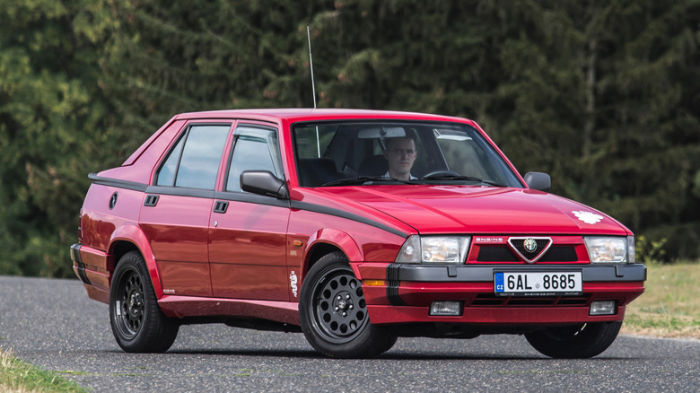 Red Alfa Romeo 75 parked on a rural road
