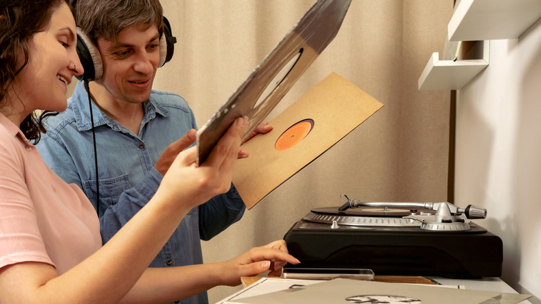 Man and woman changing out the record on their vinyl player