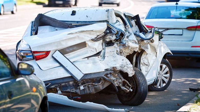 A totaled white car on the side of the road.