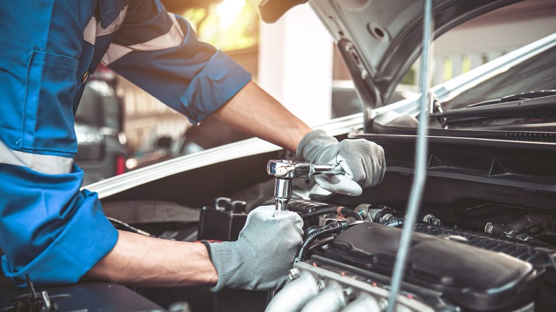 A mechanic using a ratchet on an engine.