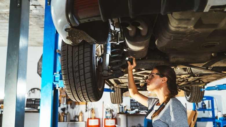 A mechanic underneath a car, inspecting the car's suspension