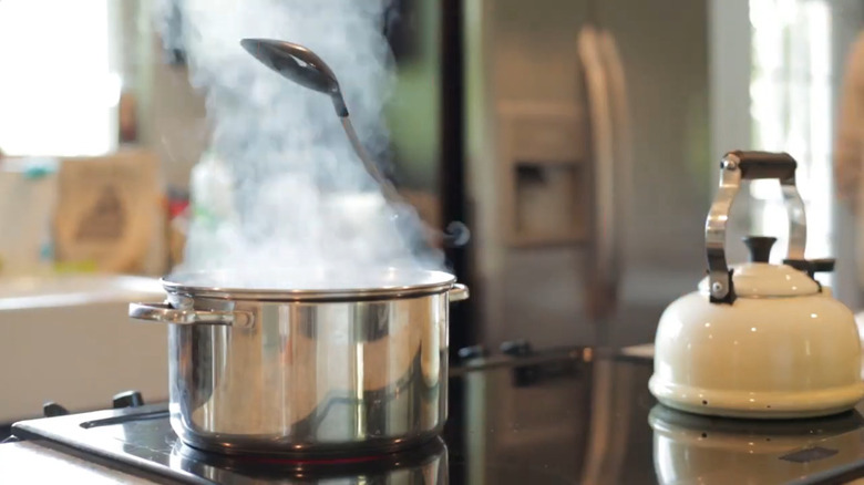 A spoon resting on the handle of a pot on the stove in a kitchen