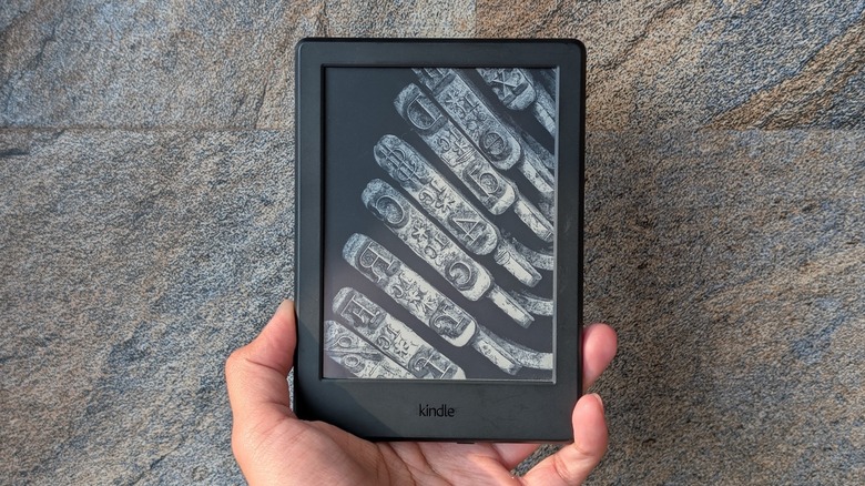 An Amazon Kindle e-reader in hand.