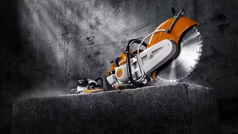 An orange STIHL Cutquik tool sitting against a concrete background with light rays shining down.