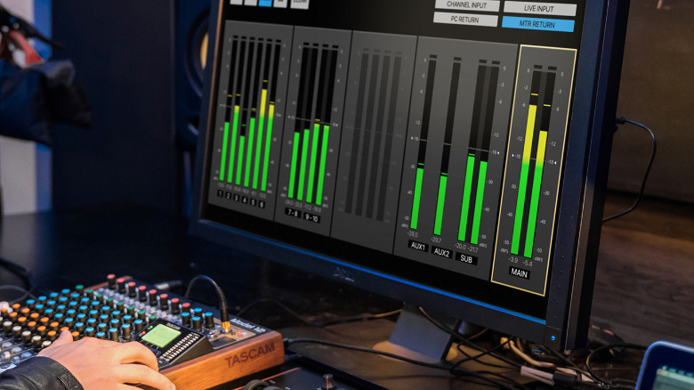 A person using the Tascam Model 12 mixer with the companion app on a PC.