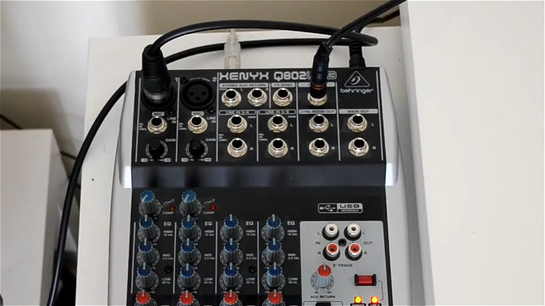 A Behringer Xenyx 802 USB mixer on a desk with cables inserted.