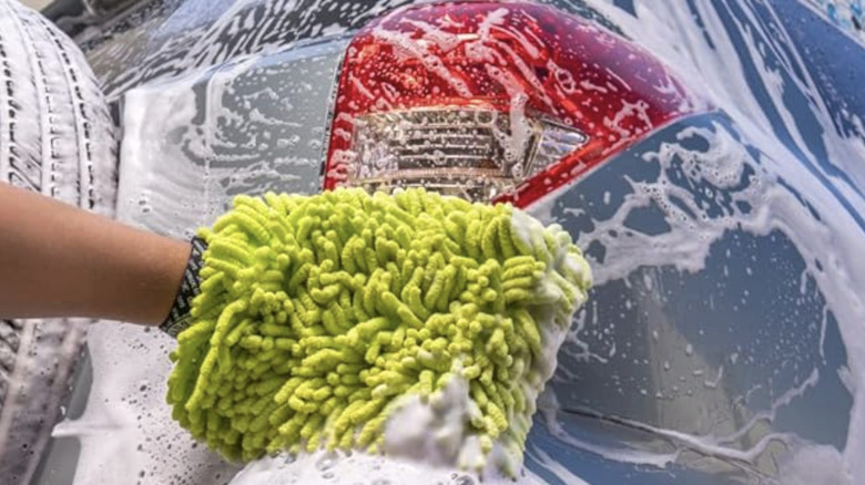 A close-up of someone washing an SUV using a green Chemical Guys car wash mitt
