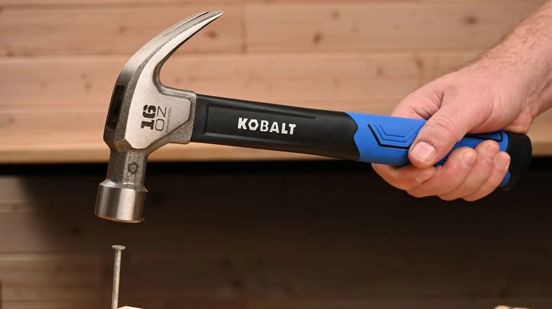 A person using a Kobalt claw hammer on a nail.