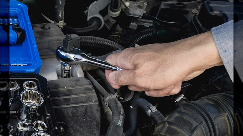 Kobalt socket set beside person using a ratchet on an engine