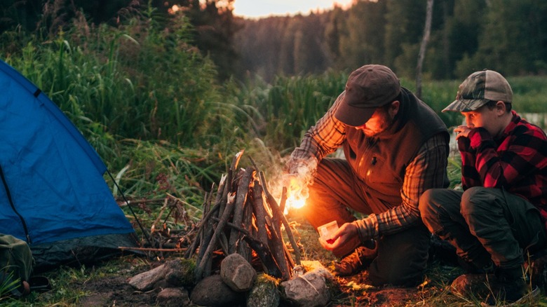 man and boy making campfire