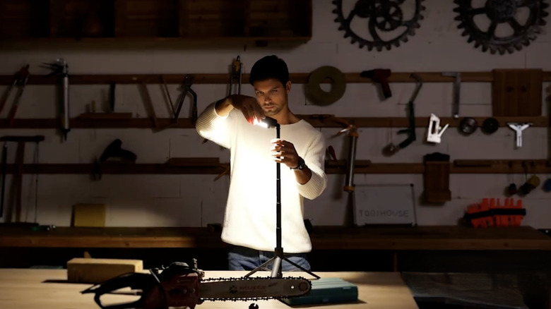 Person using Husky Tripod Light to illuminate a work table in a garage