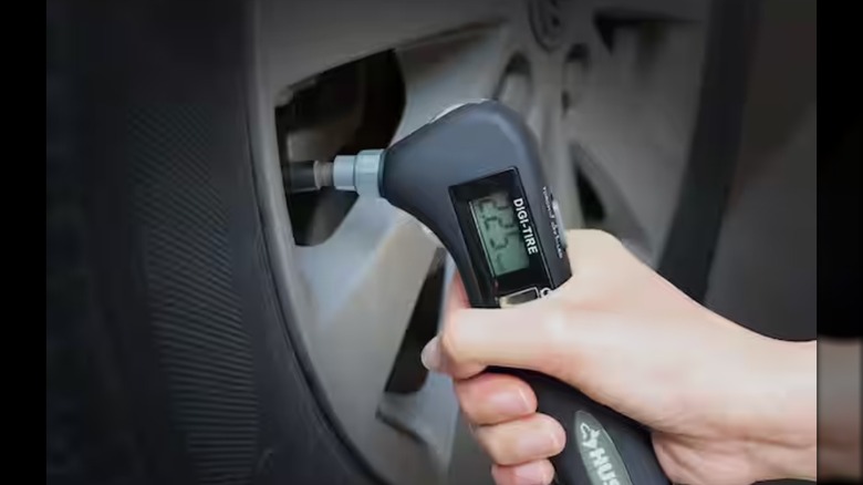 A Husky Tire Pressure Gauge being used to check a car tire's pressure