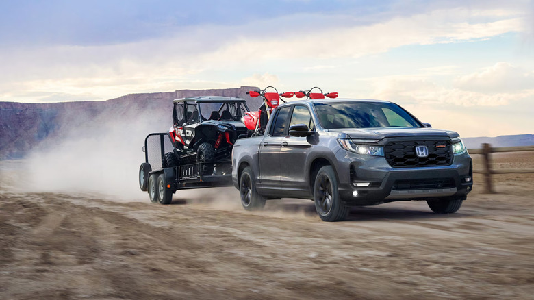 A 2026 Honda Ridgeline towing a dune buggy on a dirty road