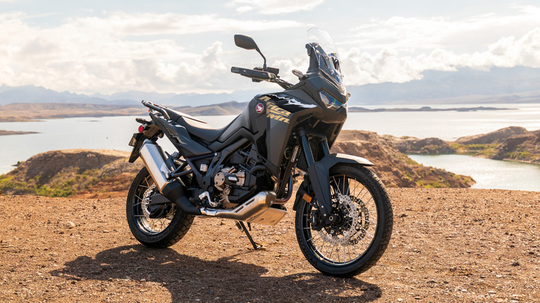 Honda Africa Twin resting on its kickstand near a lake