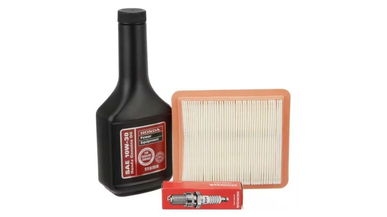Honda engine oil, filter, and spark plug on a white background.
