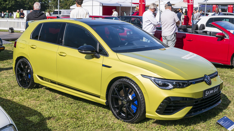 A bright yellow Volkswagen Golf R parked on a lawn.