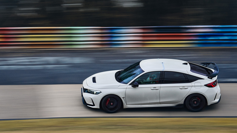 Side view of white Honda Civic Type R driving on race track.