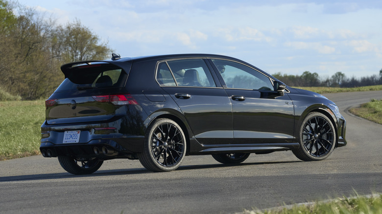 Rear 3/4 of black Volkswagen Golf R parked on race track.
